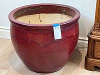 Front view of the large red glazed ceramic planter pot showing rounded shape and deep red glossy finish with subtle darker patterns.