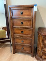 Full front view of the wooden lingerie chest showing all five drawers, wood grain, and metal knobs.