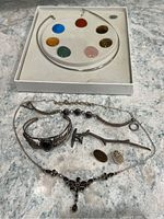 Overview of all six jewelry pieces on countertop: boxed collar necklace, bracelets, pendant, earrings and necklace
