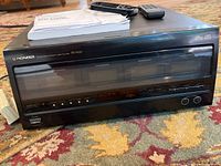 Front view of black Pioneer PD-F100 100 disc CD player, showing the front glass window, Pioneer branding, and control buttons.