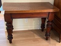 Side view of the modern oak side table showing bolster legs and drawer