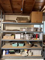 Front view of large steel shelving unit holding various items such as cardboard, boxes, plastic bins, and other small items.