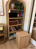 Full view of the wicker shelving unit with multiple shelves and items including pottery, books, hampered basket in front