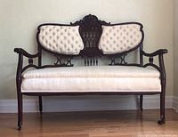 Front view of Victorian mahogany settee showing tufted cream upholstery on backrest and seat.