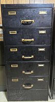 Front view of black metal filing cabinet showing all five drawers