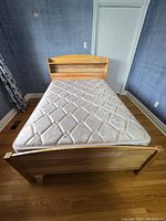 Full view of the double wooden captain's bed frame with mattress, showing headboard with bookshelf and footboard.