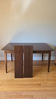 Dining table with two inserts leaning against tabletop, full view