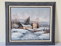 Framed oil painting of snow-covered country house and barn with surrounding trees and snowy landscape, signed M. Benson in bottom left corner.