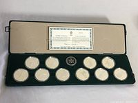 Open green velvet case showing ten silver coins in capsules and certificate under lid