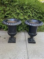 Both matching black cast iron urns placed side by side on concrete
