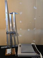 Overview of several paper trimmers, rulers, and measuring tools against a wall background showing relative size and condition.