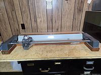 Full view of the paper and matt cutter on a table showing the wooden base, metal track, and cutter arm.