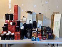 Overview of tabletop showing multiple red-boxed Paterson tanks, black plastic tanks, reels and boxes of assorted brands.