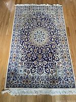 Full top view of wool area rug showing overall design, colors and fringe