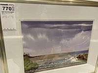 Photo of the framed watercolor artwork showing the full image with coastal landscape scene and frame.