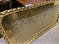 Top view of a large rectangular brass tray showing intricate etching and raised scalloped edge with hammered pattern.