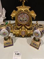 Frontal view of mantel clock flanked by pair of porcelain candlestick holders