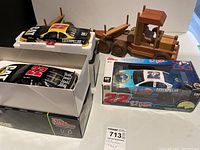 Three NASCAR model cars and a wooden logging truck on display surface