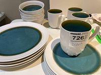View of four dinner plates, four side plates, four bowls, and four mugs arranged together showing color and design