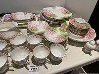 Full view of assorted plates, teacups, saucers, bowls, gravy boat, salt and pepper shakers displayed on tabletop
