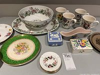 Overview of all dishes on table including mugs, ashtrays, trinket boxes, serving bowl, platter, plates.