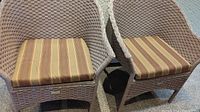 Front view of two resin wicker chairs with striped cushions