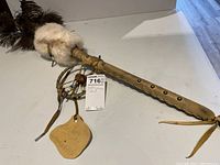 Full view of the 30-inch indigenous dance rattle with fur tuft, leather wrapped wooden handle, and stud accents.