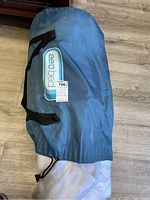 Blue storage bag containing the mattress, showing black handles and Aero Bed logo patch.