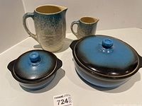 Four Medalta pottery pieces: large covered casserole, small covered casserole, large pitcher, small creamer pitcher. Blue-black gradient glaze with beige interiors, surface condition clean.
