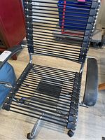 Front view showing full black elastic bungee cord seat and backrest supported by chrome metal frame and plastic armrests