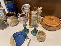 Wide view of pottery including vases, pitchers, candleholders, onyx bookends, bean pot, and plate