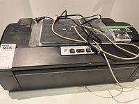 Front and top view of Epson Artisan 1430 printer with power and USB cables on top along with Maxxell 935 ink cartridge.