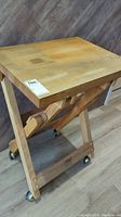 Whole table view showing the rectangular wooden top surface, light wood color, and foldable frame with wheels.