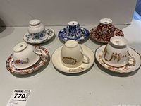 Six porcelain tea cups and saucers arranged upside down showing the base marks and pattern details on the sides.