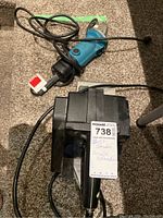 Photo showing the blue and black Makita angle grinder with a cord and plug, lying on carpet.
