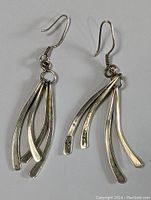 Front view of pair of sterling silver MCM earrings showing the design with curved strips hanging from hooks