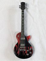 Full length guitar shaped lighter showing body, neck and headstock with flame design on body.