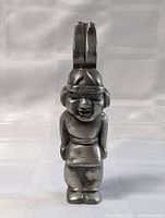 Front view of the figural metal bottle opener showing details of the character and headband inscription