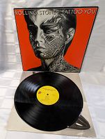 Front view of rolling stones tattoo you album cover and vinyl LP record with the yellow label visible.