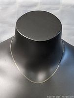 Front view of 16 inch sterling silver flat band necklace on black mannequin bust, showing chain's shine and thickness