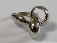 Close-up photo of a sterling silver abstract sculpture ring with smooth polished finish and Mid-Century Modern style.