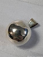 Front view of the sterling silver chime ball pendant showing its smooth polished spherical surface and bail attachment.