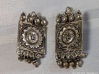 Pair of vintage sterling silver earrings with tribal sun face design, top accented with balls and bottom dangling loops.