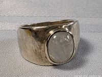 Front angle view of sterling silver ring with oval quartz stone on a light textured surface.