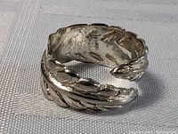 Photo of sterling silver carved leaf ring showing side and open-ended design with textured leaf carving.