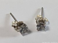 Pair of sterling silver stud earrings with clear round faceted stones, with butterfly backs visible.