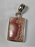 Close-up of rectangular pink tourmaline stone pendant set in sterling silver with polished silver bail.