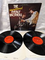 Two vinyl records from 'The Sensational Everly Brothers' album, showing the orange label and partly visible text, placed on white protective sleeves.