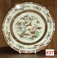 Full view of the antique plate showing floral and bird motifs with decorative border in multiple colors.