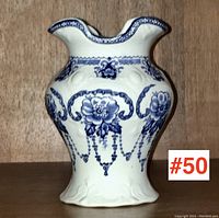 Front view of antique blue and white transferware pottery toothbrush holder with floral garland decoration.